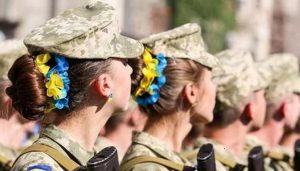 жінки у військовій формі з синьо-жовтими стрічками у волоссі на параді