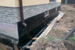 обробка фундаменту будинку бітумною гідроізоляцією перед засипкою