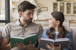 тато і донька сидять разом та читають книги вдома
