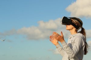Занурення у віртуальну реальність – жінка в VR окулярах на відкритому повітрі взаємодіє з віртуальним середовищем, піднявши руки